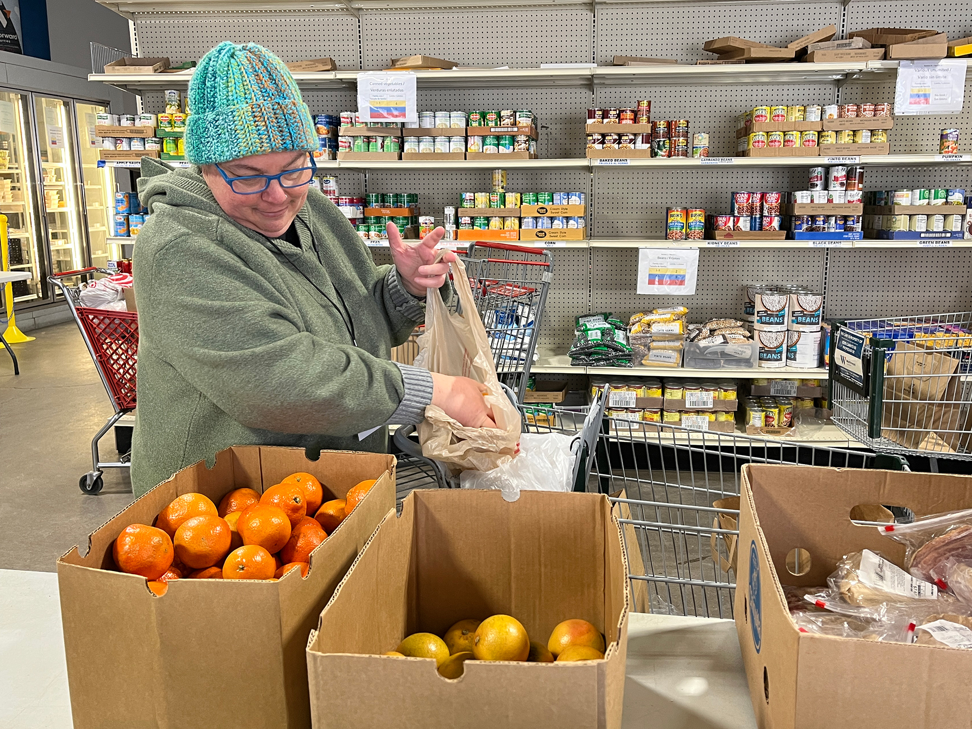 Person packing fruit into a bag with shelves behind.