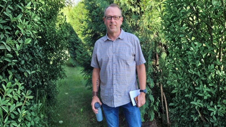 A man standing in front of a bunch of trees and shrubbery.