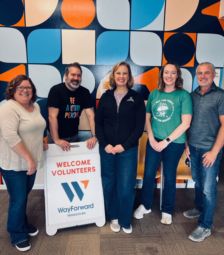 Group of volunteers in front of WayForward pattern wall with Welcome Volunteers sign.